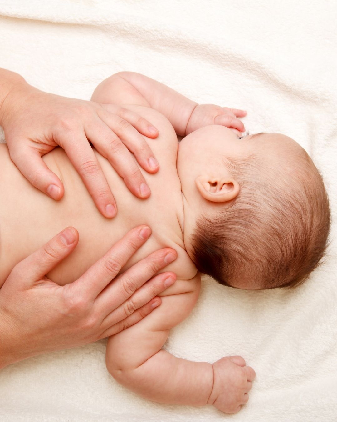 Parent's hands gently massaging a baby's chest